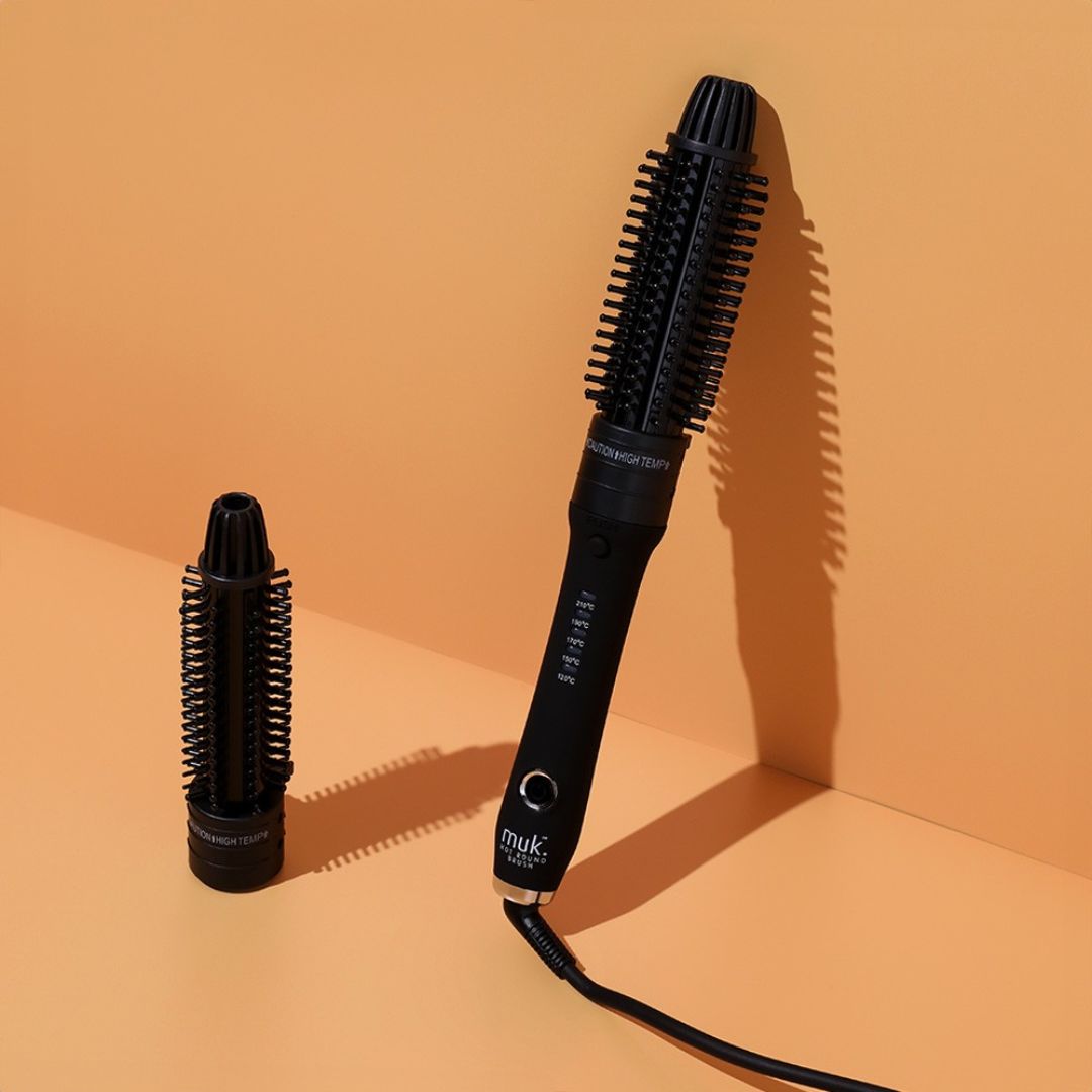 Black hair styling tool with attachments on an orange background